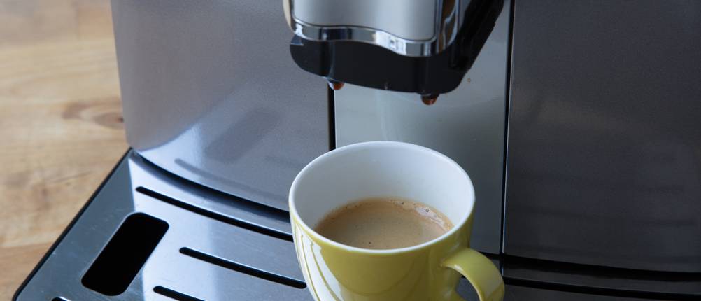 Eine Kaffeetasse steht unter einem getesteten Kaffeevollautomaten.