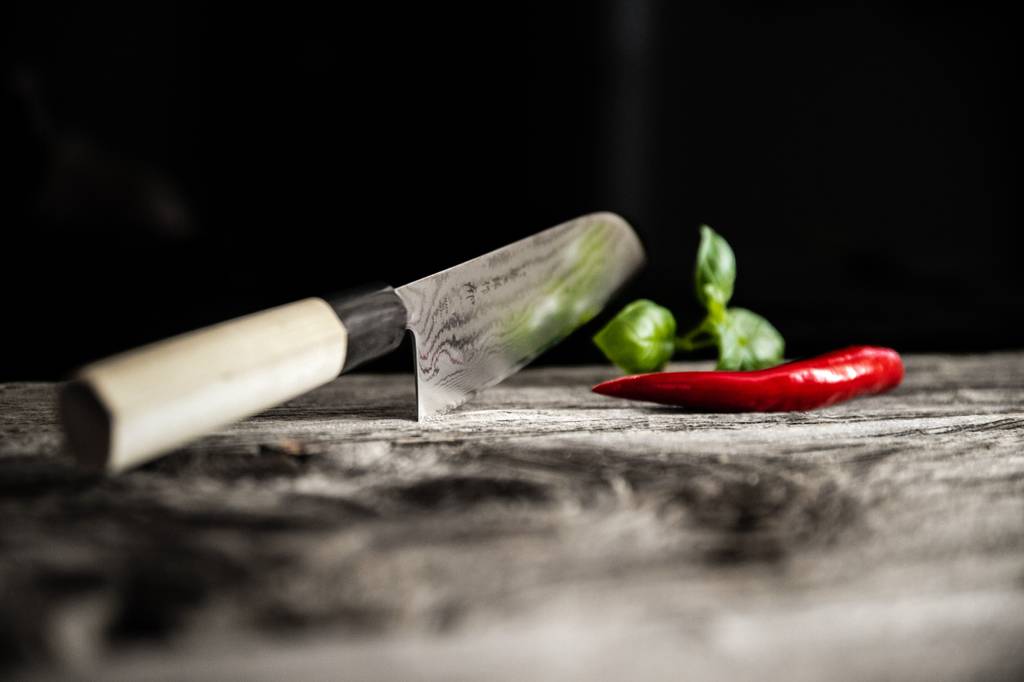 Kai-Messer-Test: Auf einem Tisch befinden sich ein Damastmesser und eine Chilischote. 
