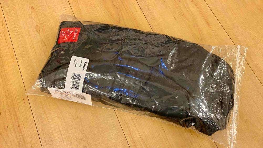 Im Test: Ein verpackter Kinderwagen-Handwärmer auf einer Holzfläche liegend.