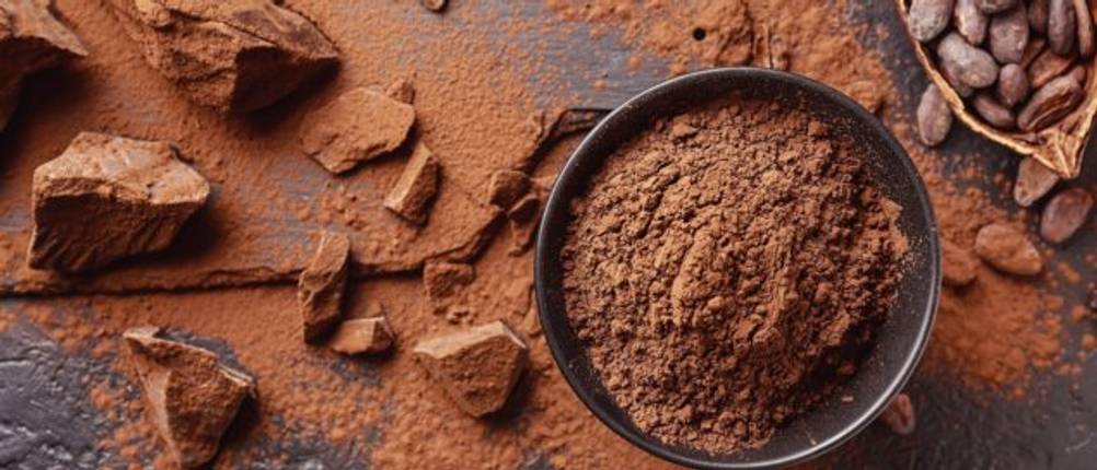 Kakaopulver mit Kakaobohnen und Schokolade auf einem Tisch.