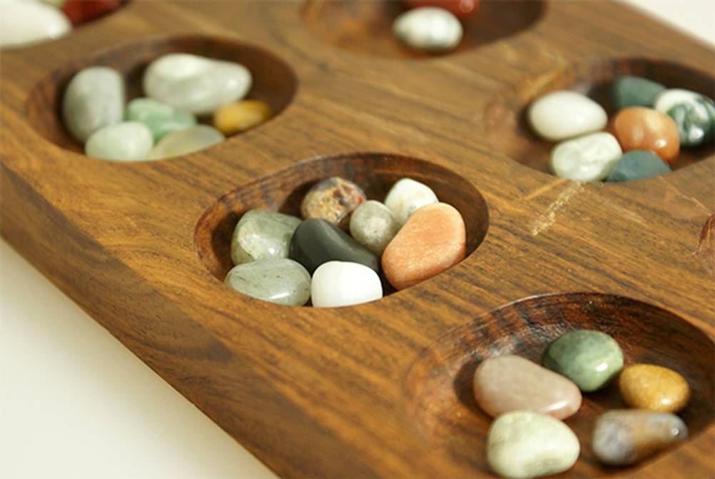 Kalaha im Test: Ein Holzspielbrett mit Spielsteinen aus Edelsteinen.