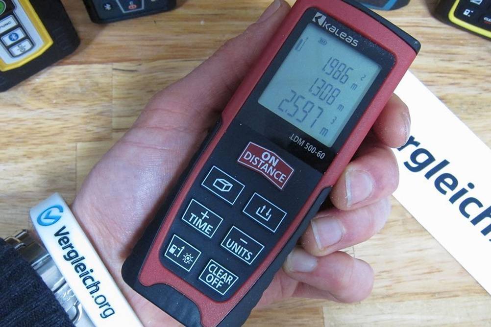 Nahaufnahme eines Laser-Entfernungsmessers, der in einer Hand gehalten wird. 