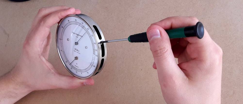 Ein mechanisches Hygrometer wird mit einem Schraubendreher kalibriert