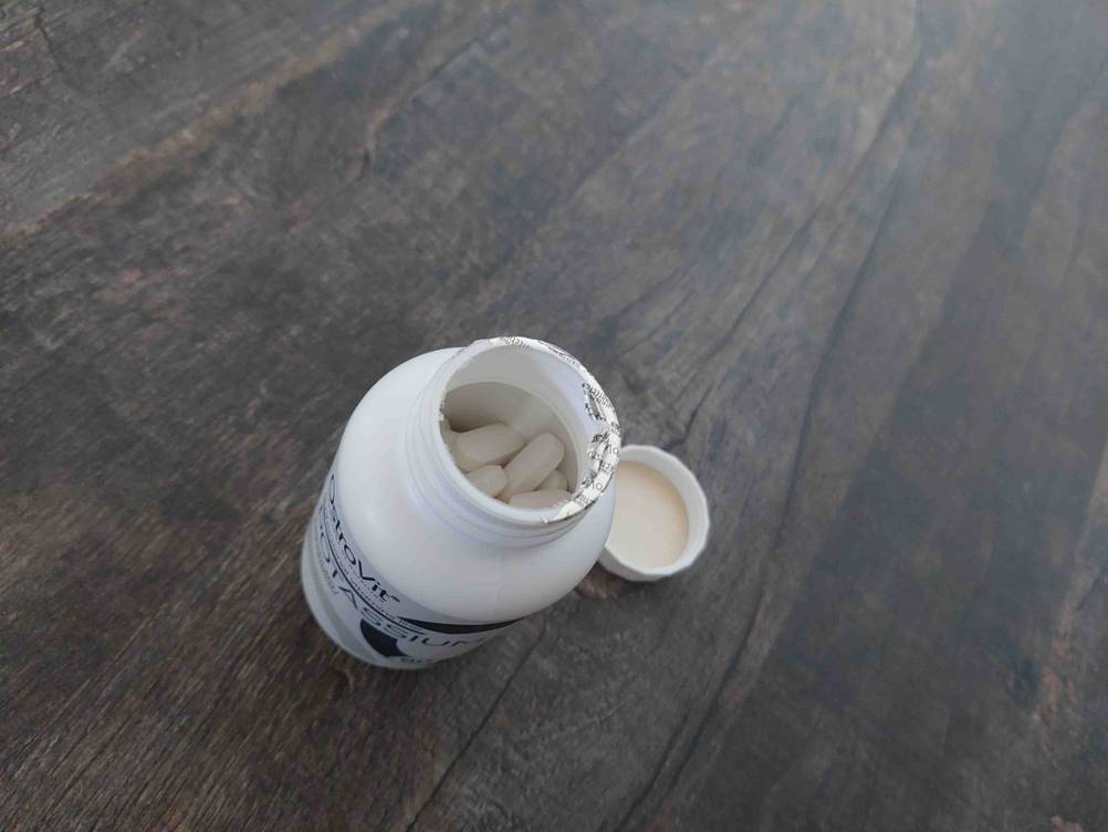Eine geöffnete Dose Kalium im Test auf einer dunklen Holzfläche, daneben die Verschlusskappe.