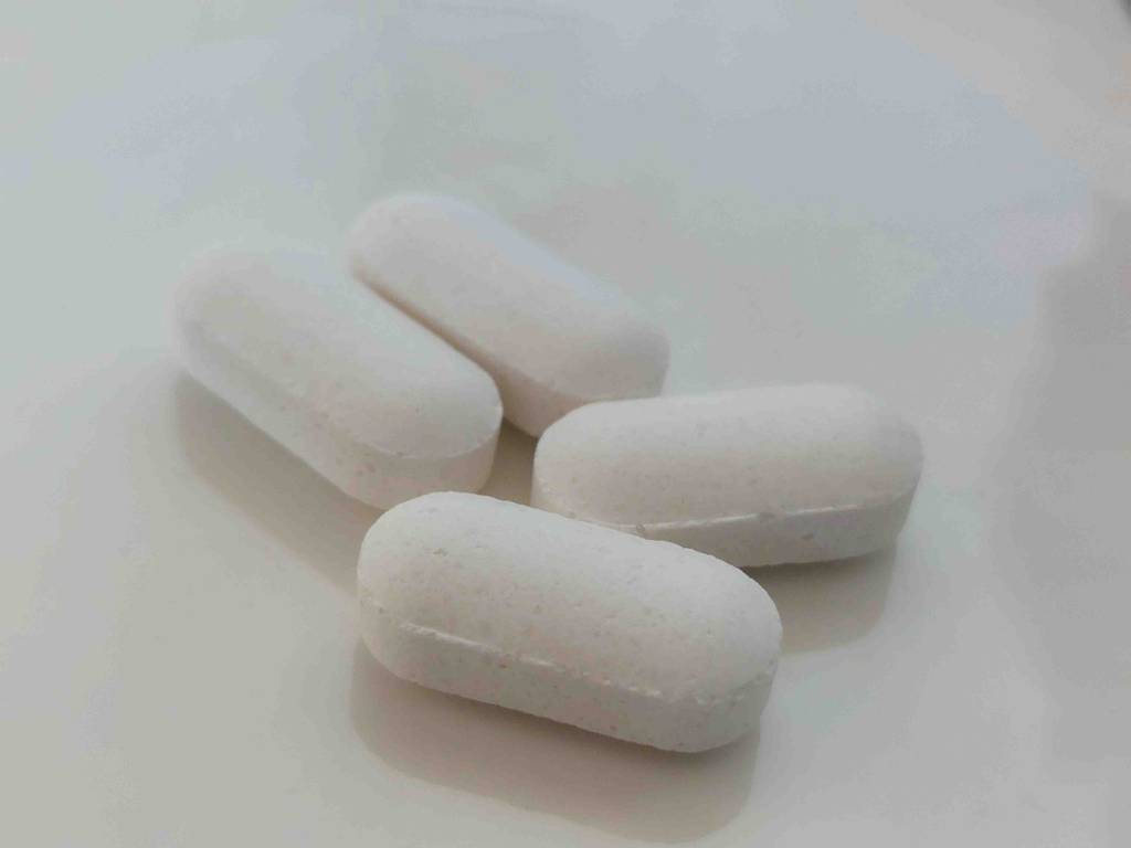 Vier getestete Kalium-Tabletten liegen auf einer weißen Oberfläche.