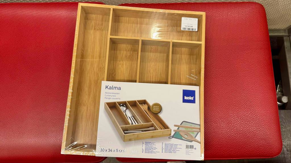 Ein verpackter Besteckkasten liegt zum testen auf einem roten Hocker.