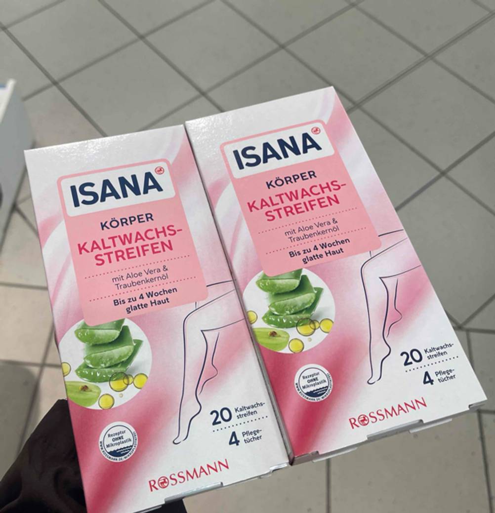 Eine Hand hält zwei Packungen Kaltwachsstreifen zum testen.