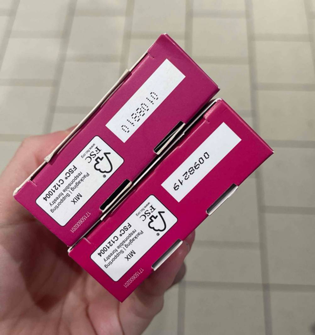 Eine Hand hält zwei Packungen der Kaltwachsstreifen Gesicht im Test mit der Unterseite nach oben.