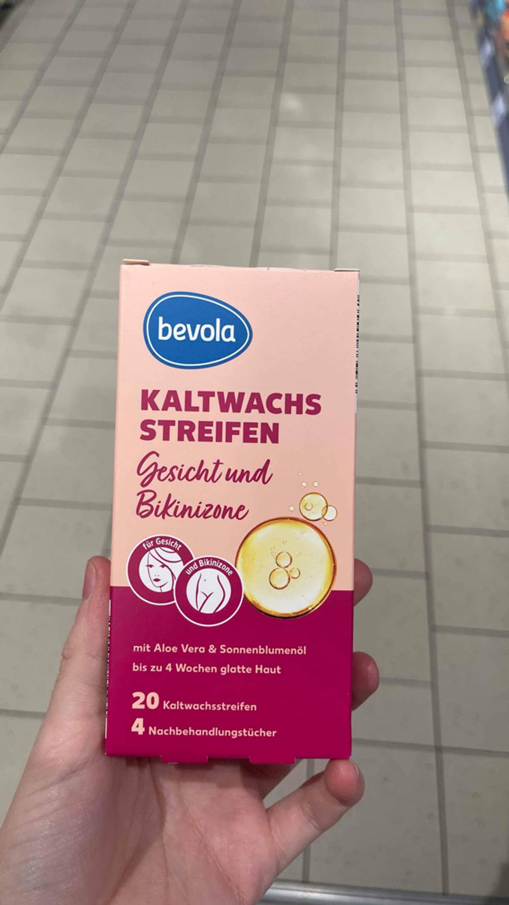 Eine Hand hält eine Packung der getesteten Kaltwachsstreifen Gesicht.