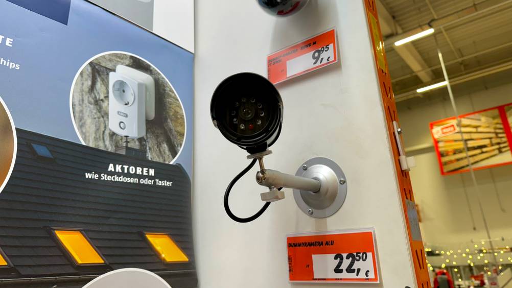 Kamera-Attrappe getestet: Ein Gerät in einer Verkaufsausstellung an einer Wand montiert mit Preisangaben.