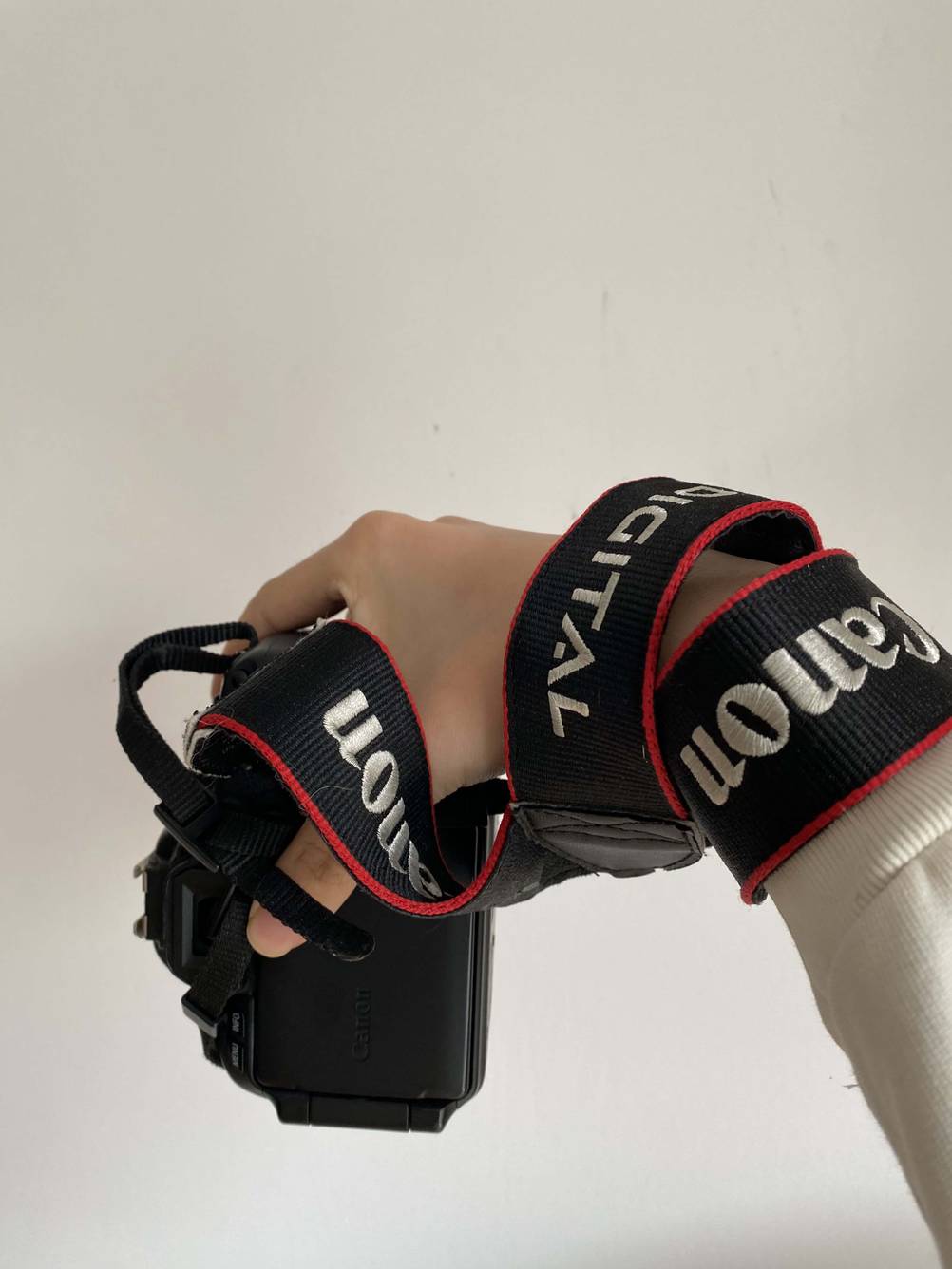 Eine Hand hält eine Kamera, die an einer getesteten Kamera-Handschlaufe angebunden ist.