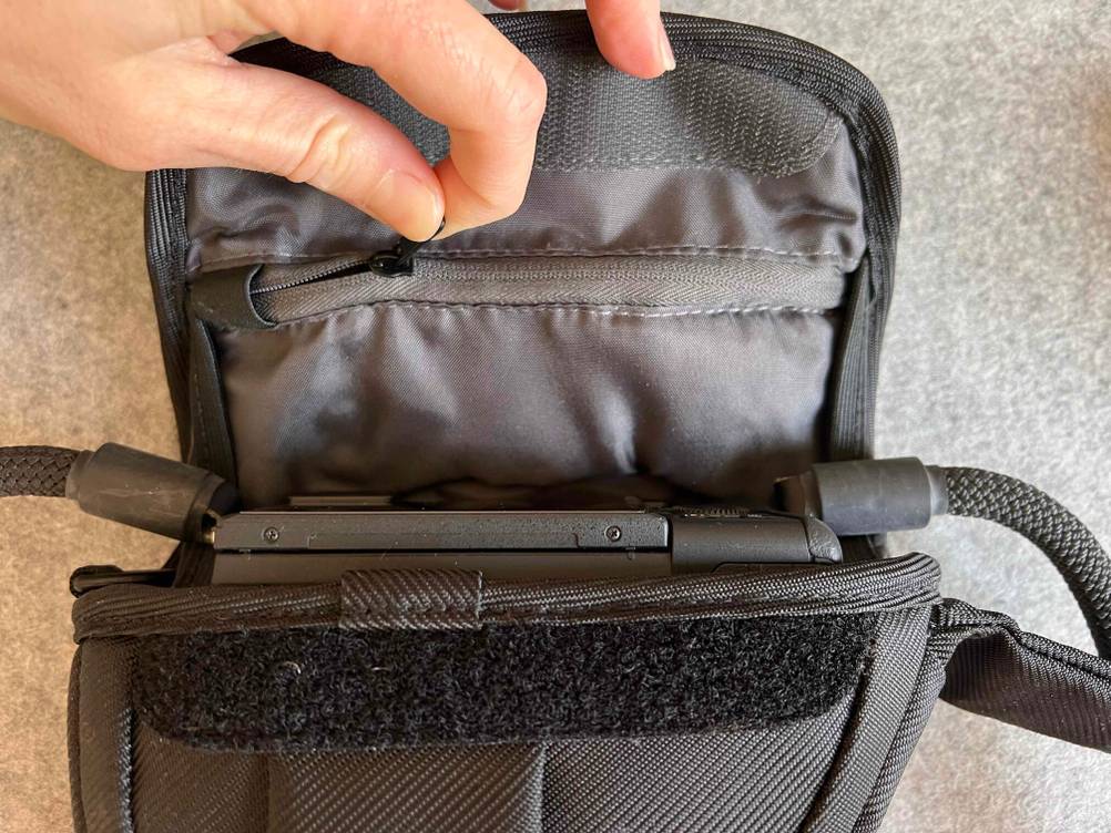 Im Test: Eine Hand öffnet die Reisverschlusstasche im Deckel einer Kameratasche.