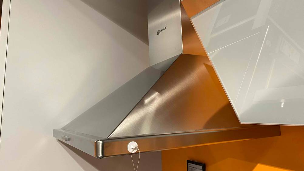 Eine getestete Kaminhaube von schräg seitlich an einer orangenen Wand.