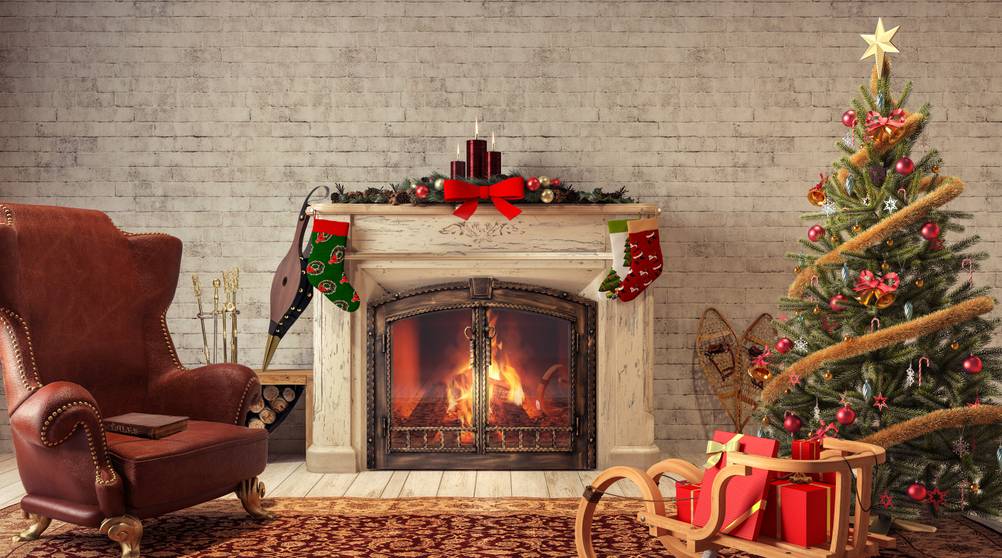 Kaminschutzgitter im Test: Nostaligische Darstellung eines Kamins mit Weihnachtsbaum und -deko sowie Ohrensessel