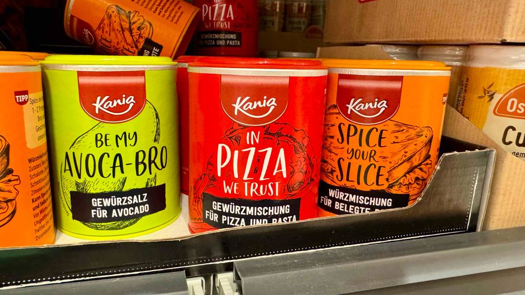 Eine getestete Pizza-Gewürzmischung steht in der Dose in einem Verkaufsregal neben weiteren Gewürzdosen.