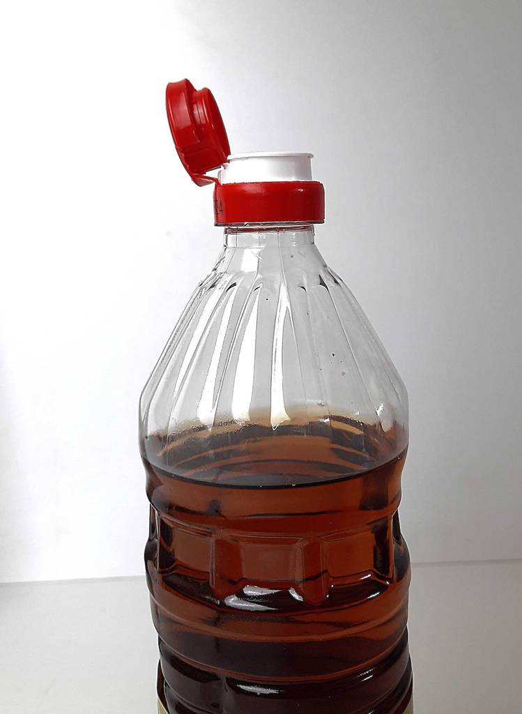 Ein getesteter Branntweinessig in der Kunststoffflasche steht geöffnet vor einer weißen Wand.