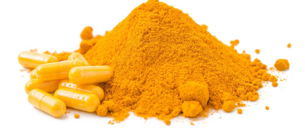 Kapselfüllmaschine-Test: Orangenes Pulver und Kapseln mit einem weissen Hintergrund. 
