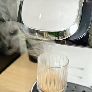 Wasserdampf steigt während des Brühvorgangs aus der Bosch Tassimo My Way 2 auf. Ein Glas steht unter dem Auslauf.