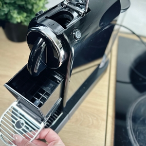 Eine Hand öffnet das Gehäuse der Citiz, um den Innenraum zu reinigen. Der Kapselbehälter ist sichtbar.