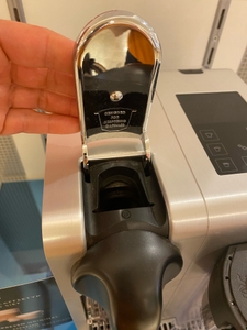 Im Test: Nahaufnahme der Kapselaufnahme an einer Kapselmaschine, Finger am Hebel.