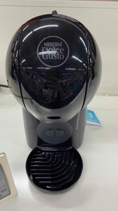 Die Kapselmaschine Nescafé Dolce Gusto in der Farbe schwarz steht auf einer weißen Oberfläche.