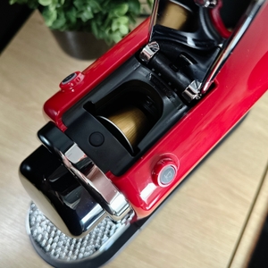 Eine goldene Kapsel ist in der geöffneten Brühkammer der Krups Nespresso XN7415 Citiz zu sehen. Die Hebelmechanik ist geöffnet.