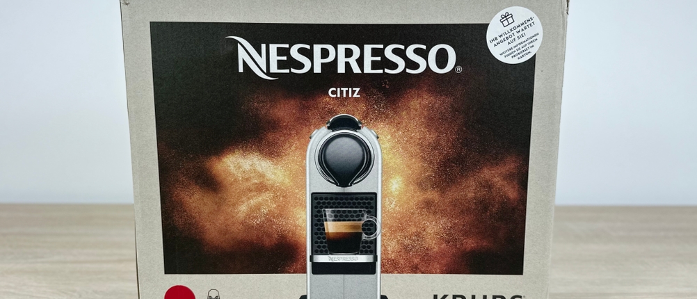 Die Verpackung der Krups Nespresso XN7415 Citiz steht auf einem Tisch. Das Modell ist mit Produktbild dargestellt.
