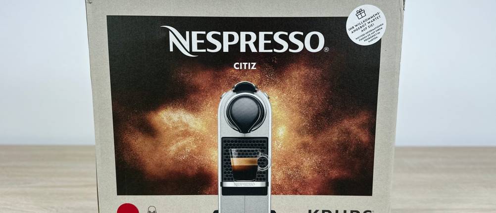 Die Verpackung der Krups Nespresso XN7415 Citiz steht auf einem Tisch. Das Modell ist mit Produktbild dargestellt.