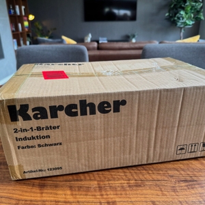 Der Karton des Karcher-Aluguss-Bräter 2-in-1 steht auf einem Tisch