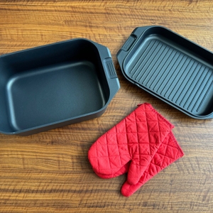 Der Behälter und Deckel des Karcher-Aluguss-Bräter 2-in-1 liegen neben mitgelieferten Handschuhen auf einem Tisch