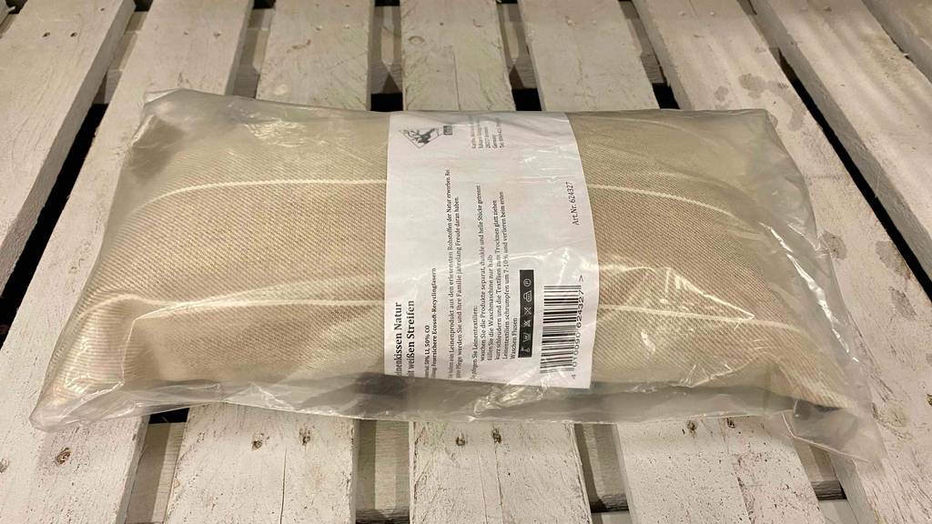 Detailansicht eines verpackten Saunakissens zum testen, das auf einer hellen Palette liegt.