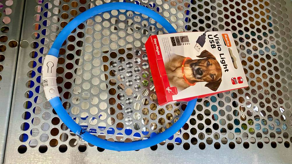 Im Test: Ein blaues Leuchthalsband für Hunde liegt auf einem Lochblech.