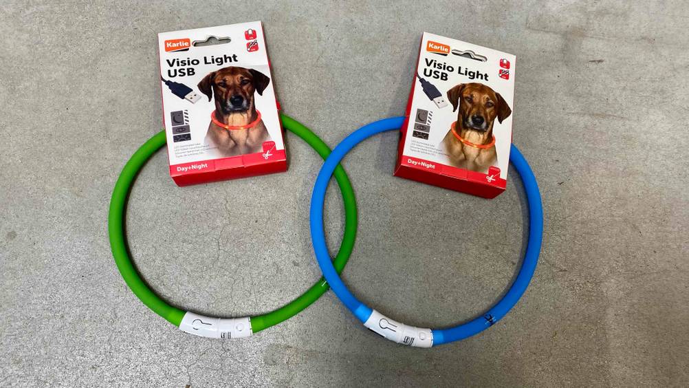 Leuchthalsband für Hunde im Test: Zwei Bänder, eines grün, eines blau, mit Label auf einem Betonboden.