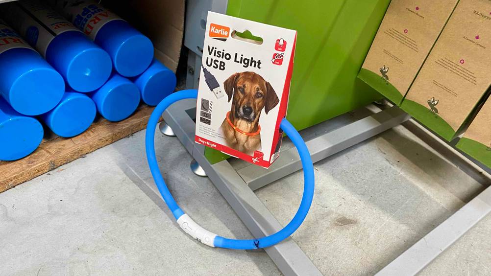 Ein getestetes Leuchthalsband für Hunde in Blau vor anderen Produkten auf dem Boden.