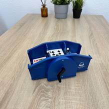 Eine Heldengut-Kartenmischmaschine mischt Spielkarten mithilfe einer seitlichen Kurbel auf einem Tisch.