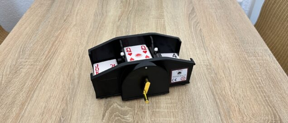 Eine Kartenmischmaschine mit Kurbel ist mit Karten gefüllt.