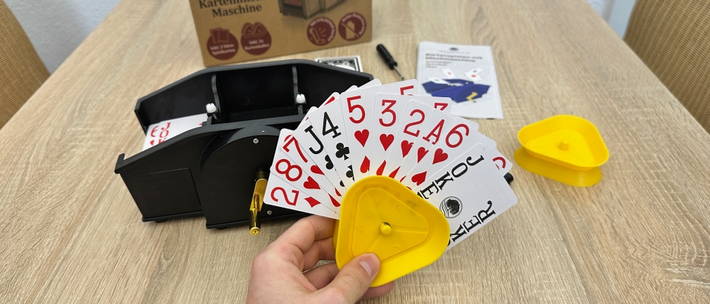 Eine Person hält elf Karten mithilfe eines gelben Kartenhalters in der Hand.