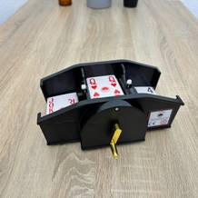 Eine Weidebach-Kartenmischmaschine mit Kurbel ist mit Karten gefüllt.