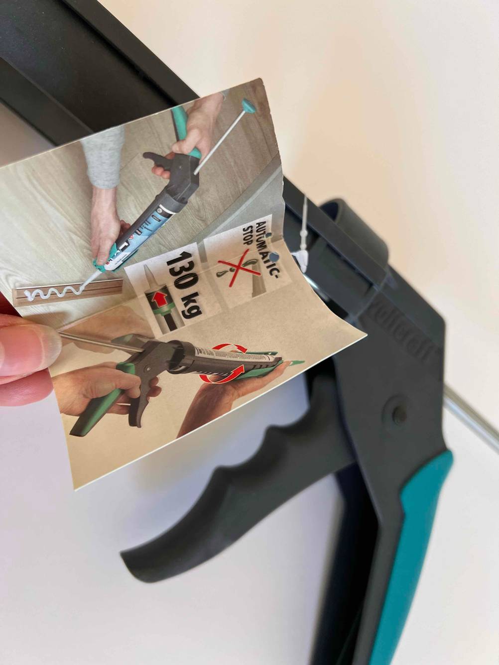 Eine Hand hält die Produktinformationen von einer getesteten Kartuschenpistole.