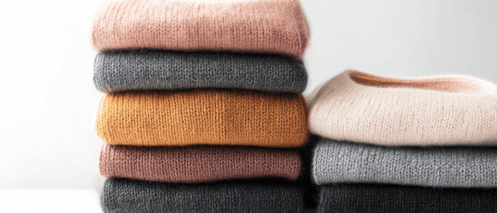 Kaschmir-Pullover-Damen-Test: Mehrere gefaltete Kaschmir-Pullover in verschiedenen Farben liegen aufeinander. 