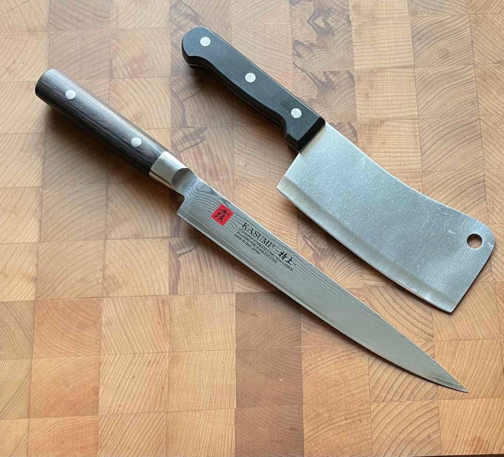 Chinesisches Kochmesser im Test: zwei Messer von KASUMI liegen schräg auf einer Holzfläche.