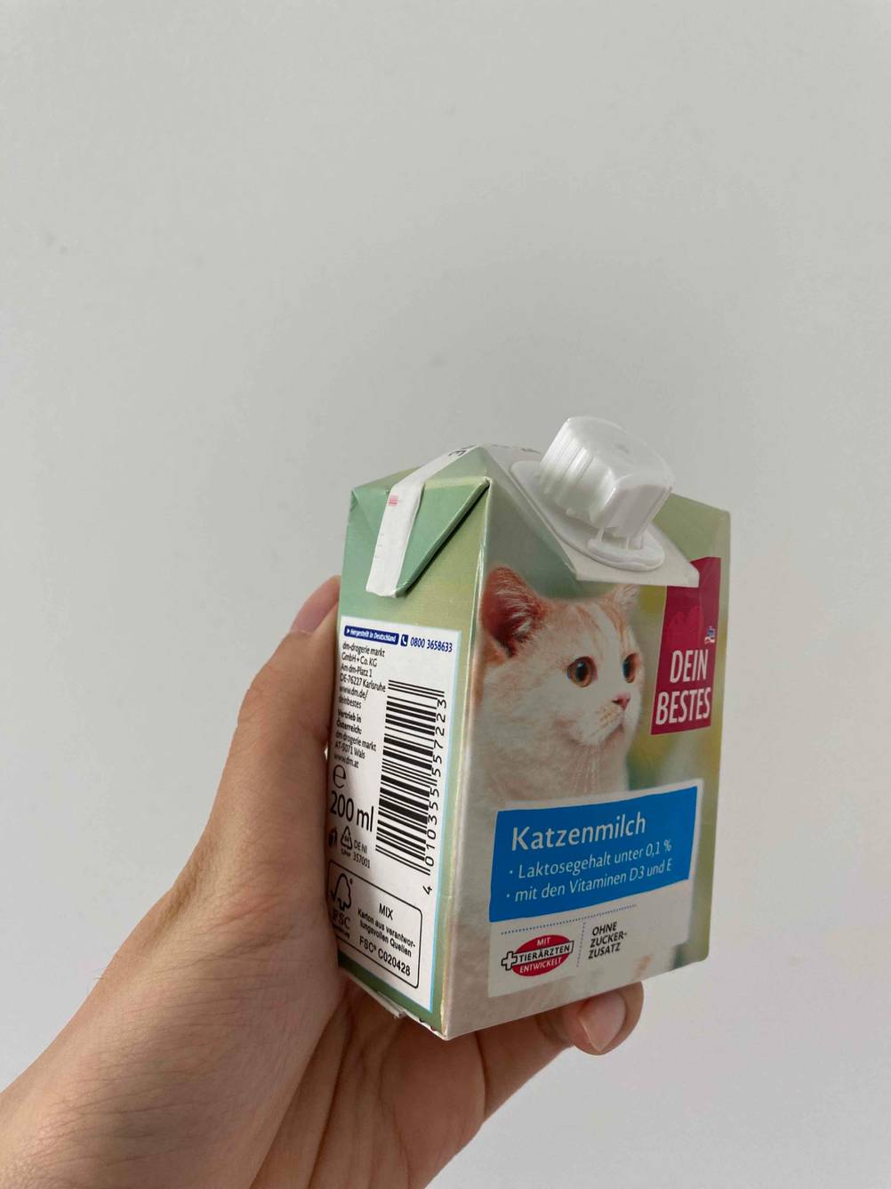 Eine Hand hält getestete Katzenmilch in einem Tetrapack. 