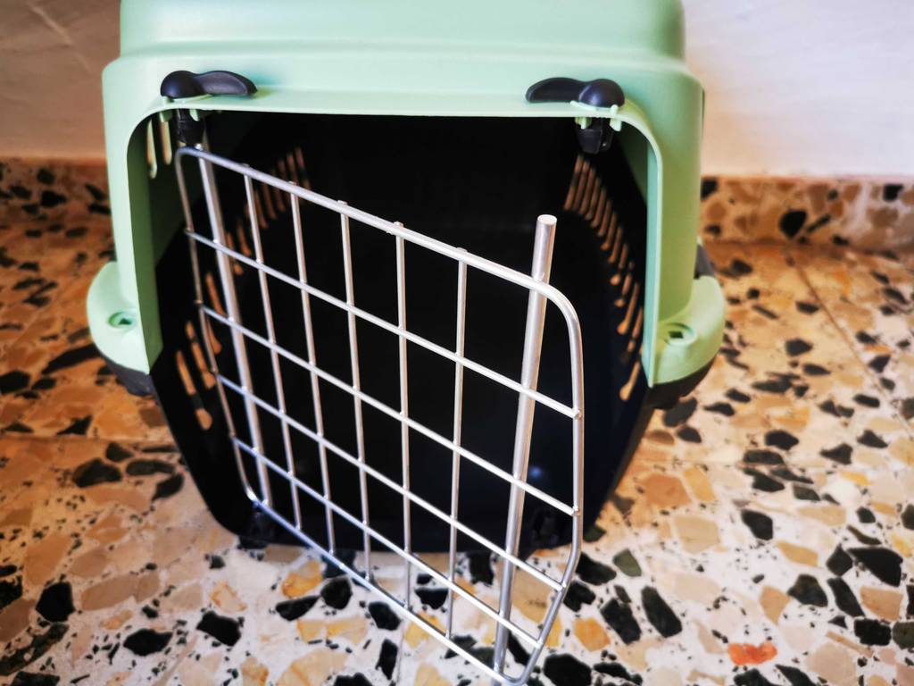 Eine getestete Katzentransportbox steht mit offener Tür auf einem Fliesenboden.