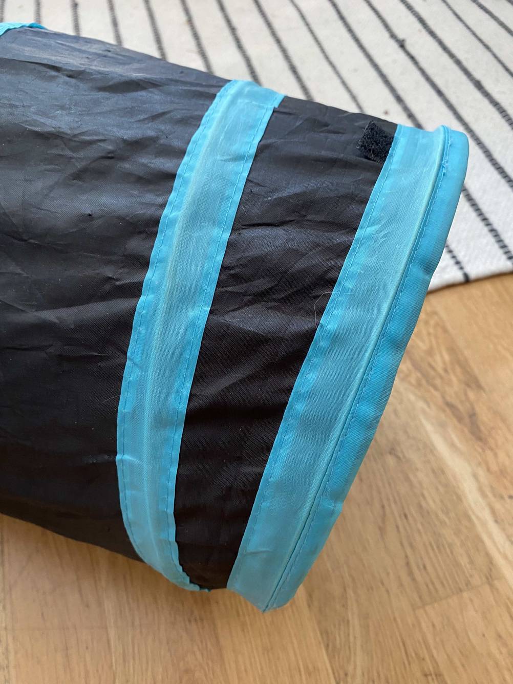 Nahaufnahme einer Öffnung des getesteten Katzentunnels auf einem Holzboden.