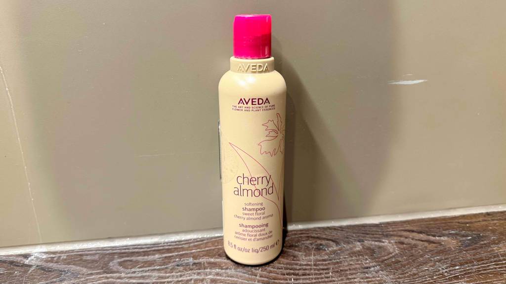 Getestet: Ein Aveda-Shampoo in der beigefarbenen Kunststoffflasche steht vor einer dunklen Wand.
