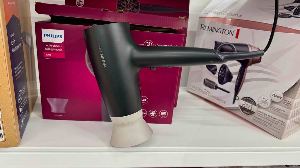 Der Philips-Haartrockner im Test ist vor seiner roten Verpackung auf einem Regal ausgestellt.