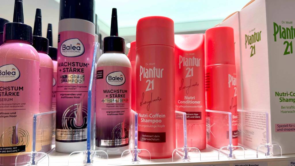 In einem Regal befindet sich das getestete Plantur-Shampoo in roten Kunststoffflaschen neben weiteren wachstumsfördernden Shampoos.