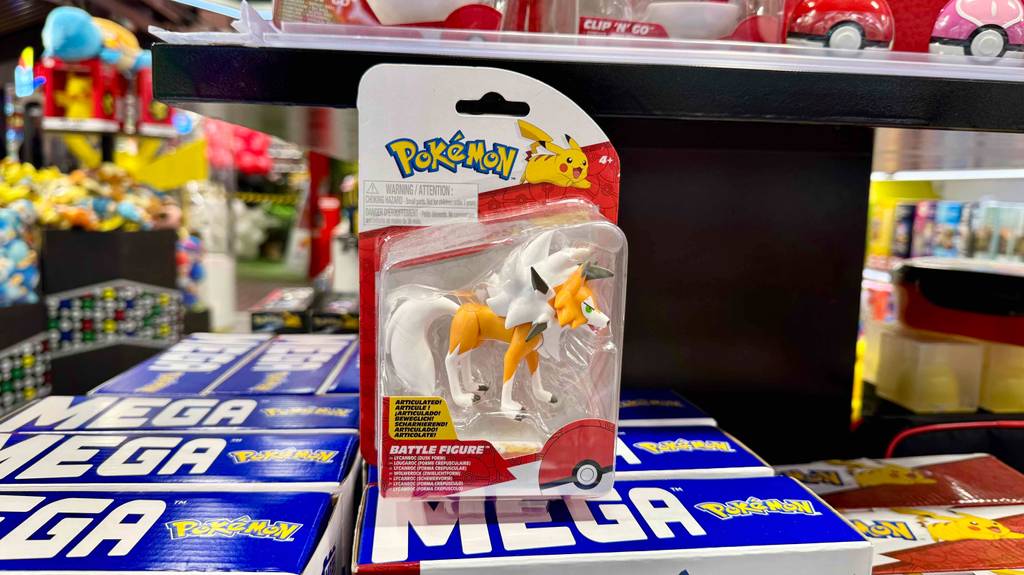 Eine getestete Pokémon-Figur in der Verpackung steht auf weiteren Spielzeugen in einem Verkaufsregal.