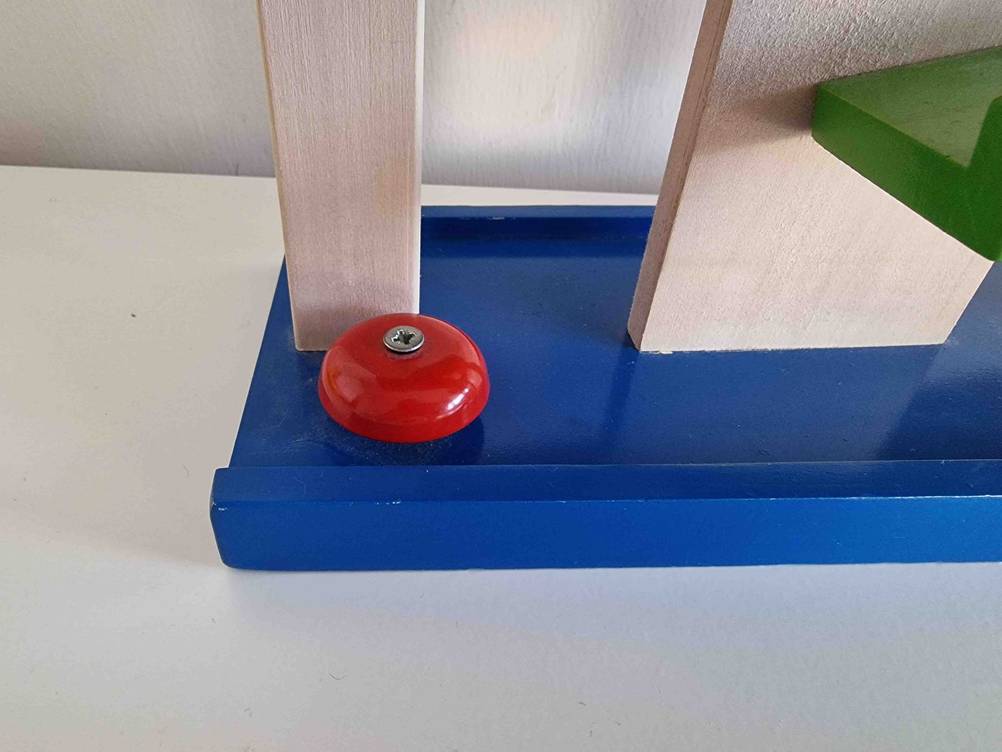 Nahaufnahme von schräg oben von einer bunten Holz-Kugelbahn im Test inklusive festgeschraubtem Stopper, der die Kugeln, nach Herunterfallen, anhält.