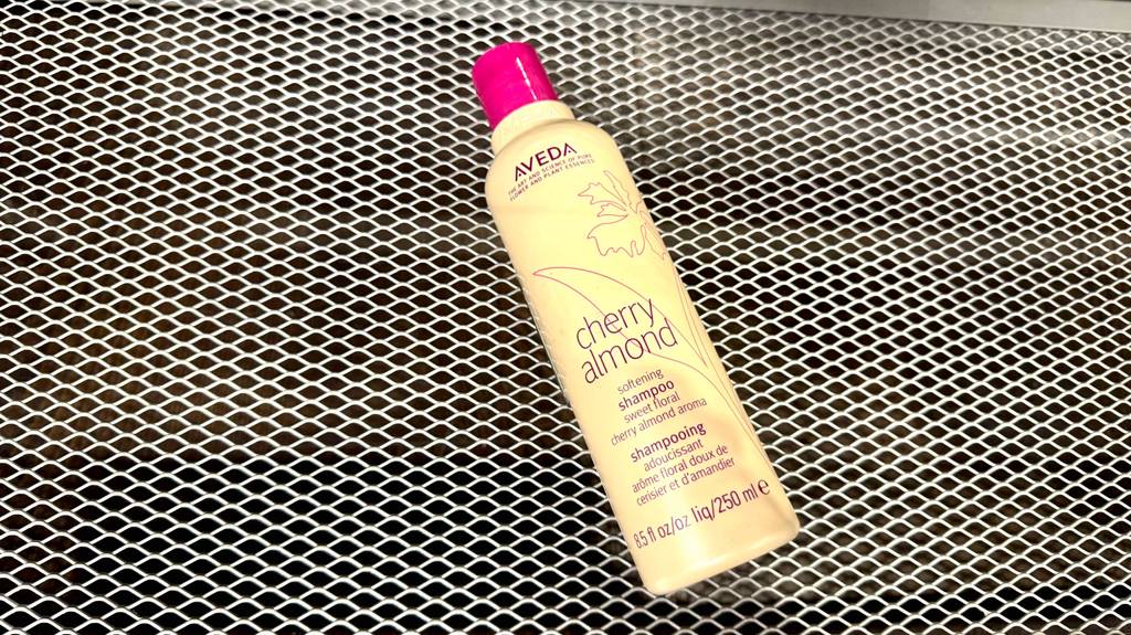 Im Test: Aveda-Shampoo in der beigefarbenen Kunststoffflasche liegt auf einem Gitteruntergrund.